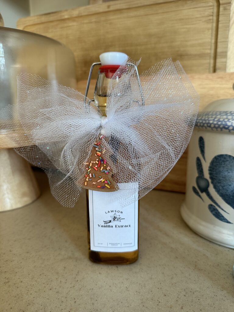 bottle of homemade vanilla extract with a bow on it and a small gingerbread tree ornament